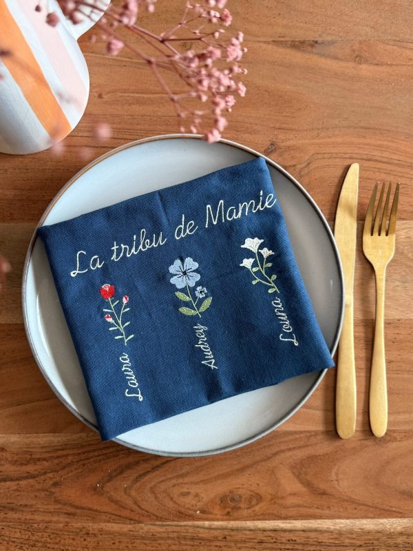 Serviette de table brodée la tribu de mamie posé dans une assiette
