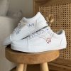 Baskets basses mariage sur un banc. Broderie fleurie et deux mains liées