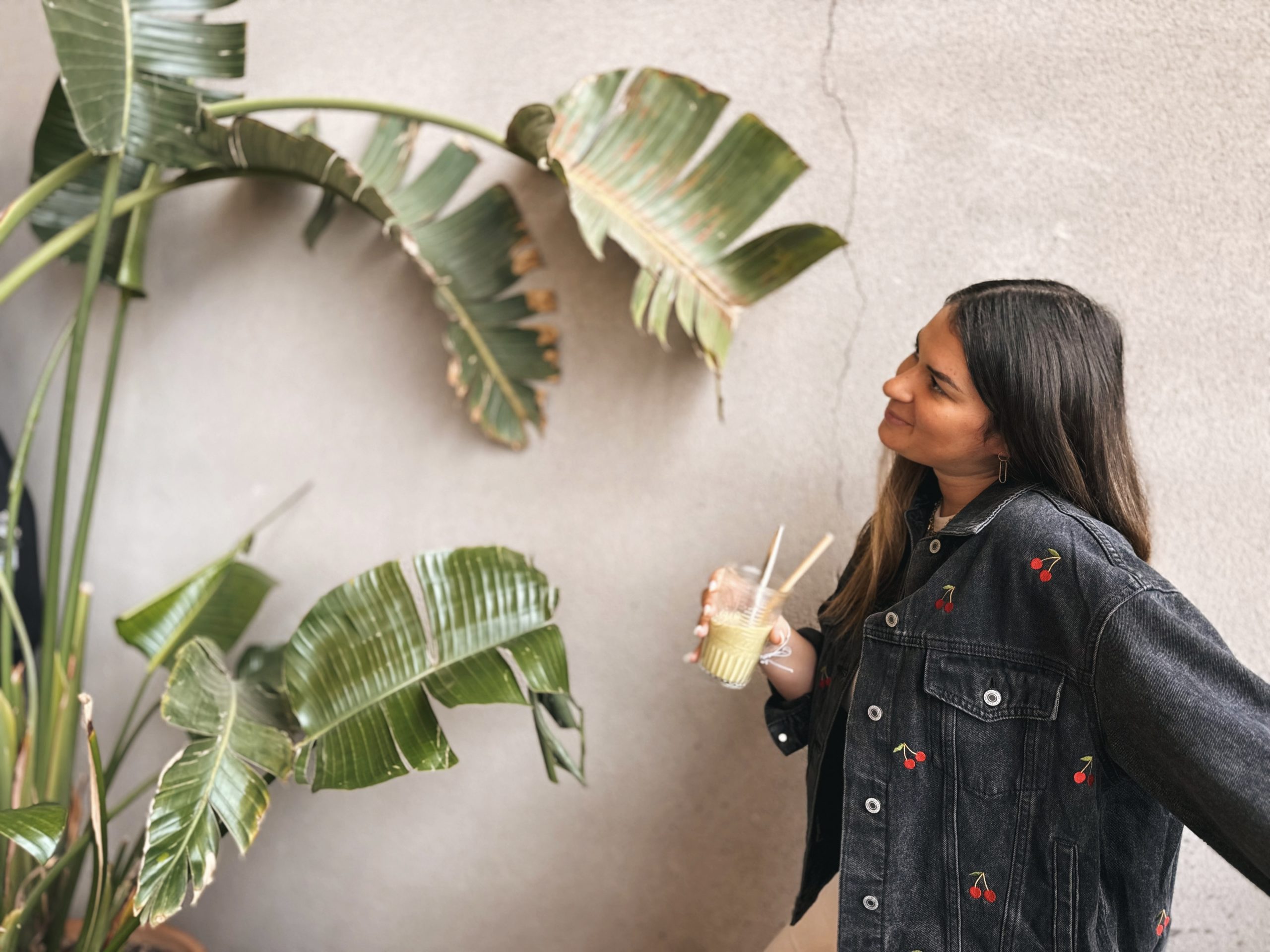 Femme avec une veste en jean brodée et un verre de matcha