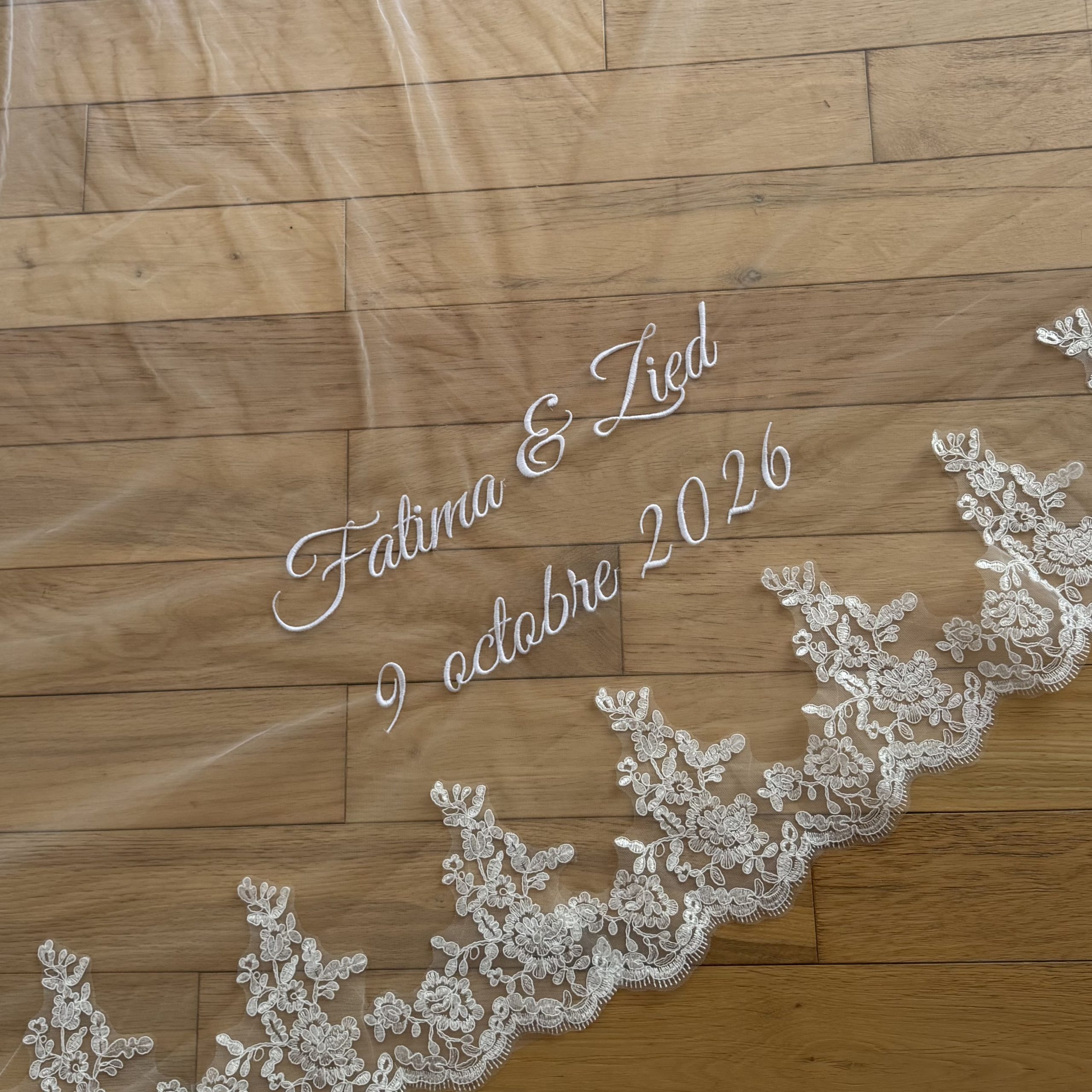 Voile de mariée brodé posé sur du parquet